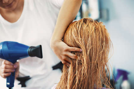 Young beautiful blonde woman enjoying hair treatment.の写真素材