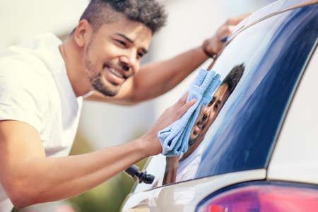 Young handsome man is washing car outdoor.の写真素材