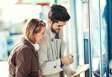 Young tourists in the city taking money from ATM.の写真素材