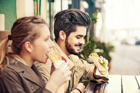 Young couple is eating sandwiches and enjoying.の写真素材