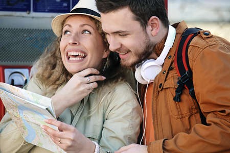 Tourist couple using telephone booth and looking at city map.の写真素材