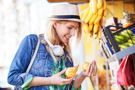 Young woman is looking for pear at green market.の写真素材