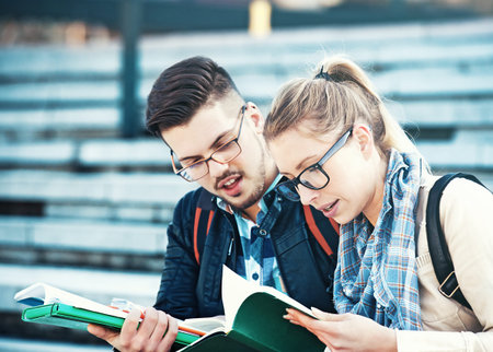 Student couple  outdoors, reading books. Learning for exam.