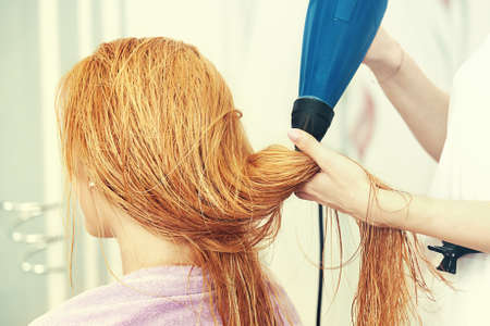 Young beautiful blonde woman enjoying hair treatment.の写真素材