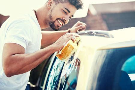 Young handsome man is washing car outdoor.の写真素材