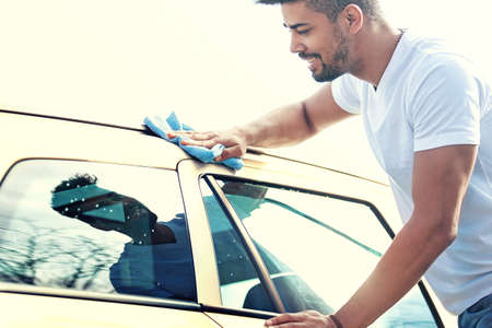 Young handsome man is washing car outdoor.の写真素材