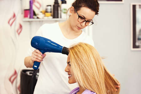 Young beautiful blonde woman enjoying hair treatment.の写真素材