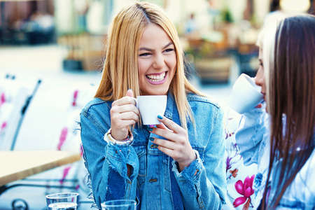 Happy young women having fun and drinking coffee.の写真素材