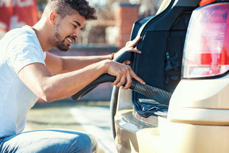 Young handsome man is cleaning car outdoor.の写真素材