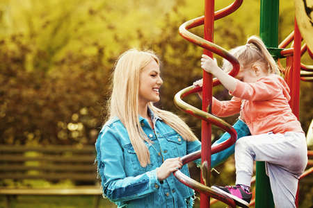 Happy family of two. Blonde mum and daughter in the park.の写真素材