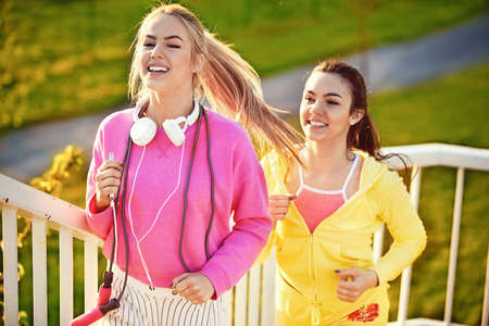 Two attractive and sporty girl friends exercising on the bridge. Living healthy lifestyle.の写真素材