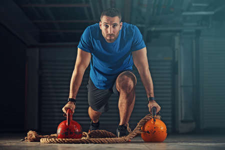 Young athlete man is training with kettlebell in garage.の写真素材