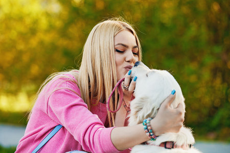 Young blonde woman is relaxing in the park with her retriever.