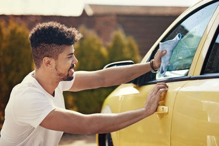 Young handsome man is washing car outdoor.の写真素材