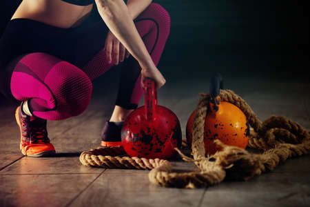 Young athlete woman exercising with kettlebell in garage.の写真素材