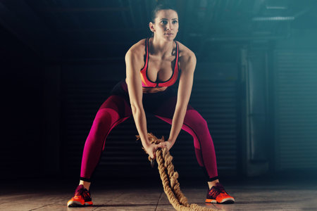 Young athlete woman is exercising  with rope in garage.