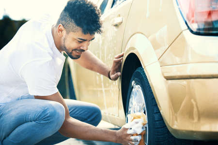 Young handsome man is washing car outdoor.の写真素材