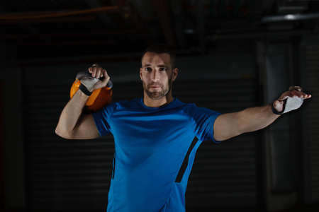 Young athlete man is exercising with kettlebell in garage.の写真素材