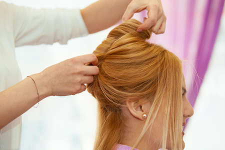 Young beautiful blonde woman enjoying hair treatment.の写真素材