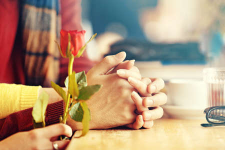Young couple enjoying restaurant in the morning. Hands and rose. Close up Concept.の写真素材