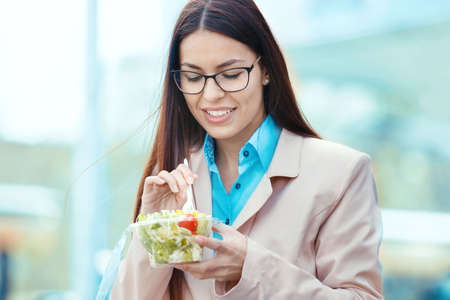 Young businesswoman eating salad on lunch break.の写真素材