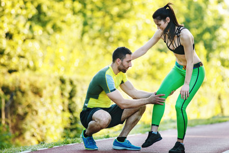 Early morning workout. Happy couple exercising.Woman has injury and her partner is helping her.