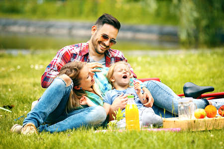 Happy family of three enjoying their time together in the park.の写真素材