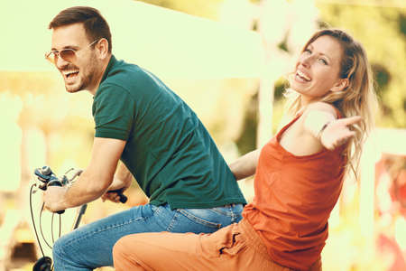 Portrait of happy young couple riding a bike in the city.の写真素材