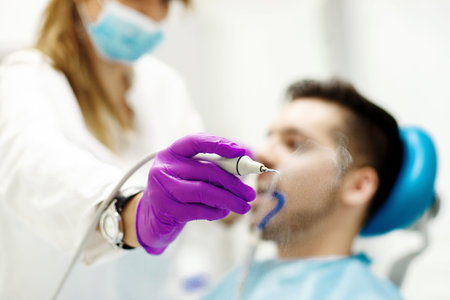 Female dentist and young man patient in dentist office.