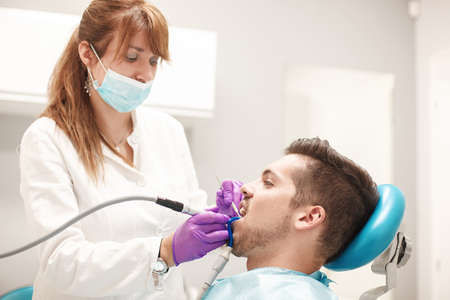 Female dentist and young man patient in dentist office.の写真素材
