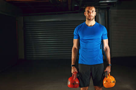 Young athlete man is relaxing after training with kettlebell in garage.の写真素材