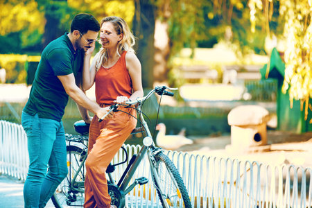 Portrait of happy young couple riding a bike in the park.の写真素材