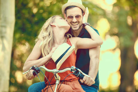 Portrait of happy young couple riding a bike in the park.の写真素材
