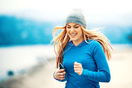 Young blonde woman is jogging on the beach.の写真素材