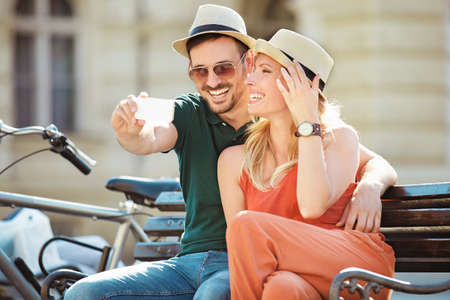 Portrait of happy young couple using cellphone in the city.の写真素材