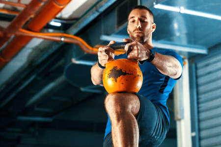 Young athlete man is having training with kettlebell in garage.の写真素材