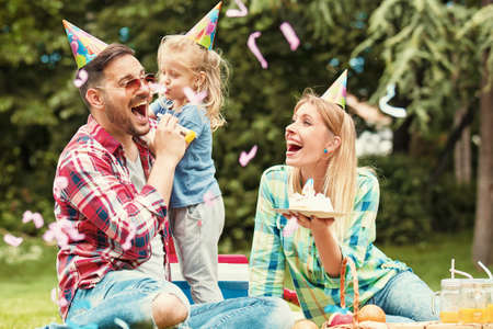 Happy family of three celebrating birthaday party in the park.の写真素材