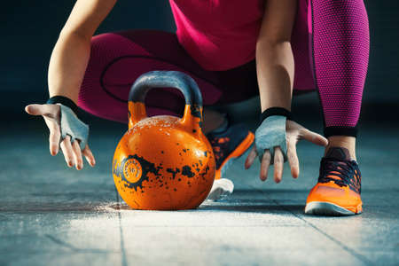 Young athlete woman is having training with kettlebell in garage.の写真素材