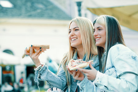 Young happy women is having fun and eating pizza.