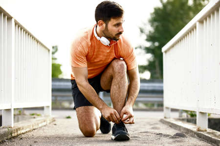 Young handsome man is preparing for exercising on the bridge.の写真素材