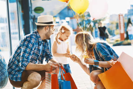 Happy family with shopping bags and ballons walking on street.の写真素材