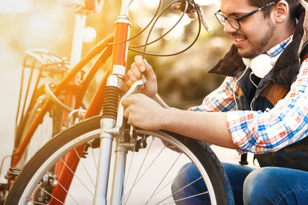 Young handsome man is checking brake on his bike.の写真素材