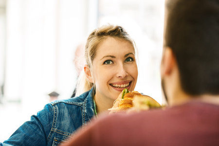 Young couple is enjoying morning and eating sandwiches.