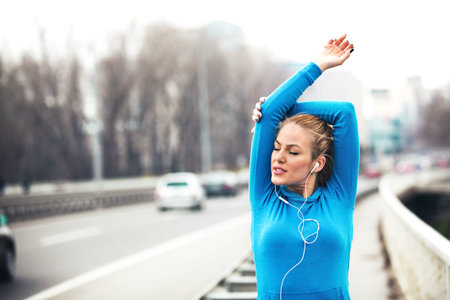 Young blonde woman is training on the bridge early in the morning.
