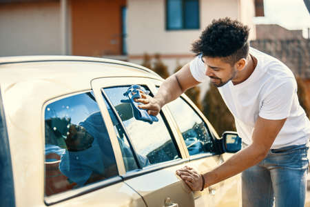 Young handsome man is washing car outdoor.の写真素材