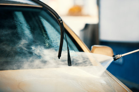 Young handsome man is washing car outdoor.