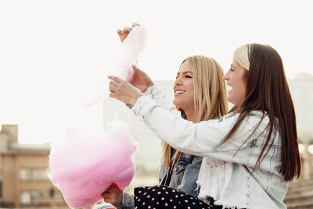 Happy young women having fun in the city and eating cotton candy.の写真素材