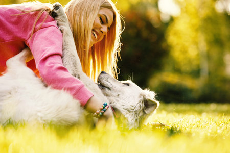 Young blonde woman is relaxing in the park with her retriever.