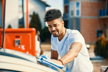 Young handsome man is washing car outdoor.