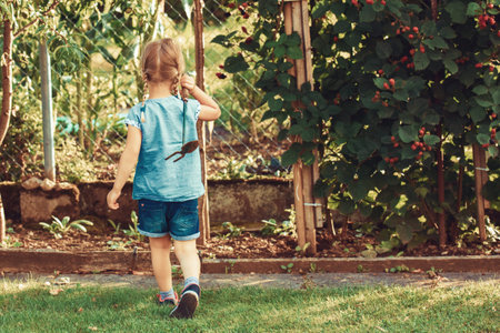 Young girl is ready for hoeing garden with small hoe.